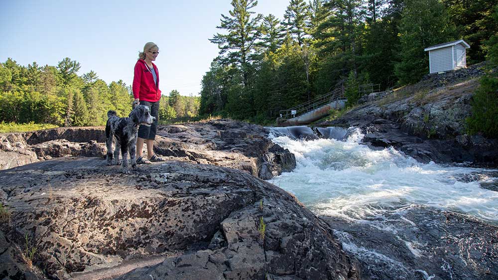 woman and dog by small rapids